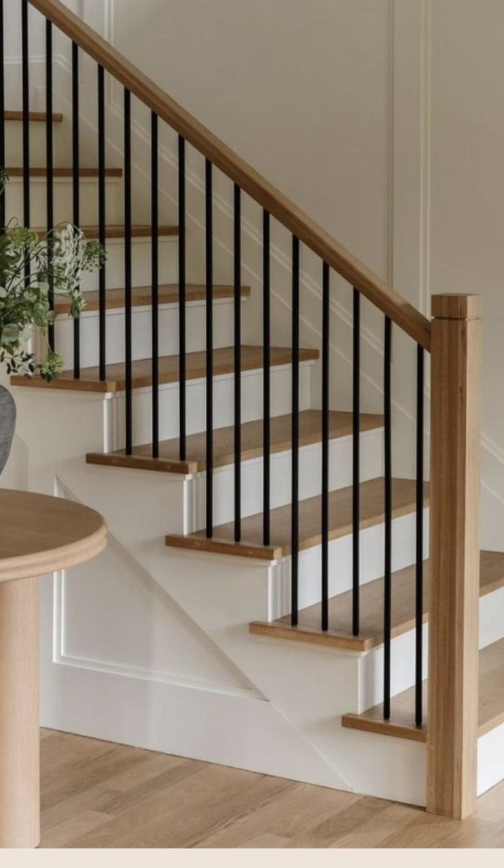 Reference image: wood handrail and newel posts with thin black metal balusters